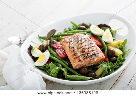 Grilled salmon nicoise salad with potatoes, olives, salad leaves