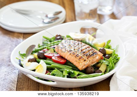 Grilled salmon nicoise salad with potatoes, olives, salad leaves