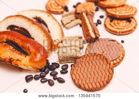 There are Pieces of  Roll with poppyseed,Cookies,Halavah,Chocolate Peas,Tasty Sweet Food on the White Background.Toned