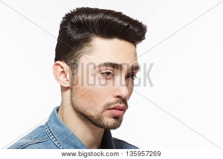 Closeup portrait of handsome man with black hair demonstrating his modern hairstyle over white background in studio. Hairdressing concept.