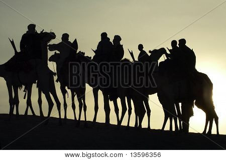Silhouette di un gruppo di Tuareg su cammelli