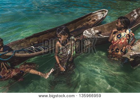 Denawan Island Sabah Malaysia - April 30 2016 : Shot of a group of people in batik traditional clothing pulling their wooden boats to start their day.