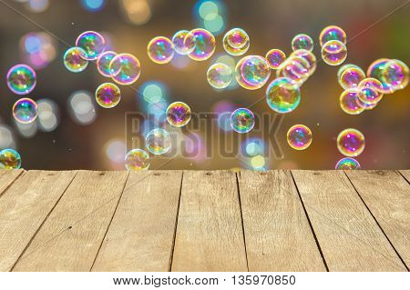 Empty wooden table or plank with bokeh of rainbow soap bubbles from the bubble blower on background for product display.