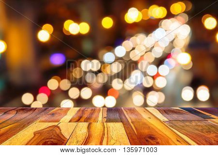 Empty wooden table or plank with bokeh of light from road or street with city tower on background for product display.