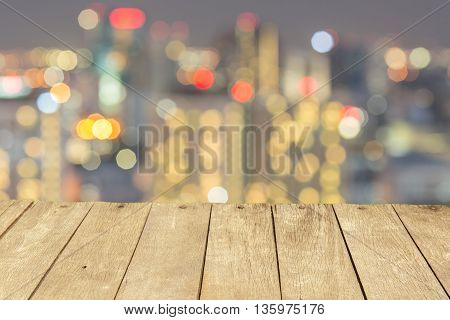 Empty wooden table or plank with bokeh of light from city tower on background for product display.