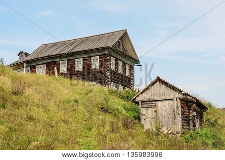 Old big log house and a shed in russian village Vologda region. Summer day