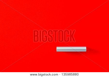Modern cylindrical metal handle in the bottom right corner on a vivid wooden red cabinet in a full frame background view with copy space