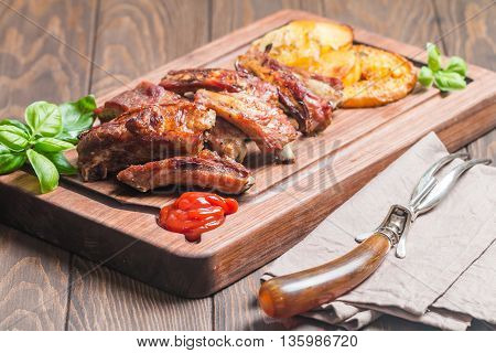 elicious Grilled Pork Rib and Fried Potato Wedges with Sauce on wooden cutting board