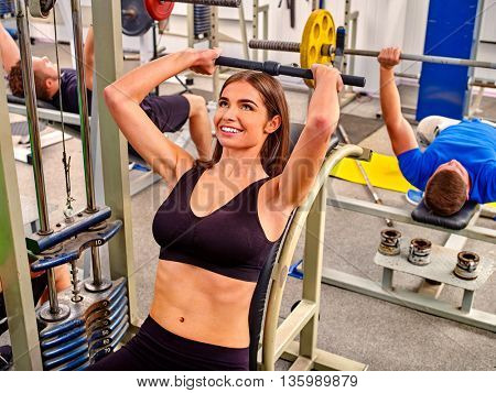 Woman working his arms and chest at gym. Bicep curl machine.