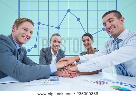 Business workers gather their hands together during a meeting in front of digital screen with graphi
