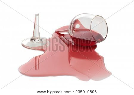 Broken glass and spilled red wine on white background