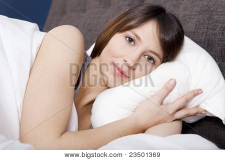 Porttrait de uma jovem bonita e natural na cama