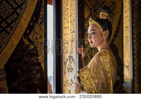 Beautiful Asia Woman In Gorgeous Antique Thai Dress Stand Near Ancient Gold Threads Old Thai Pattern