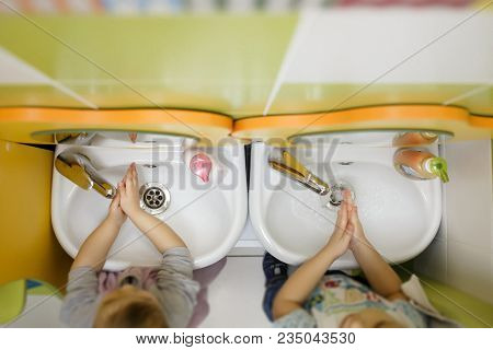 Two Children Washing Hands In A White Basin With A Bar Of Soap. Kindergarten Or Nursery Washing Room