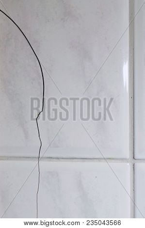 Cracked Tiles On The Bathroom Wall Need Repair. Possible Sign Of Water Damage. Vertical Image Of Bui