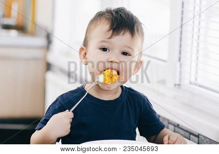 A Child In The Kitchen Eats Eggs Or Omelets In The Afternoon