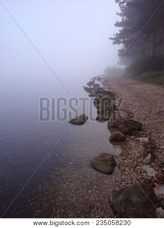 Calm Water Flowing Over Smooth Rocks At The Lake Shore