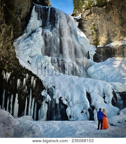 Happy Couple In Love Near Waterfall. Frozen Waterfall Near Callahan.  Alexander Falls. Whistler Vill