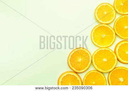Sliced Oranges On Green Background, Top View. Minimalistic Flat Lay Of Citrons On Bright And Vivd Co