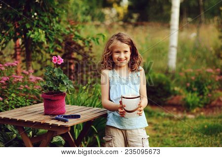 Happy Child Girl Decorating Evening Summer Garden With Candle Holder. Smiling Kid Helps On Backyard 