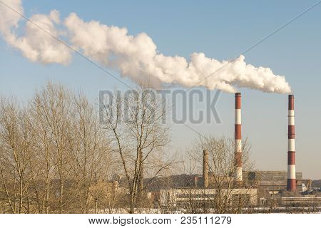 Two Large Smoking Pipes Against The Blue Sky. White Thick Smoke