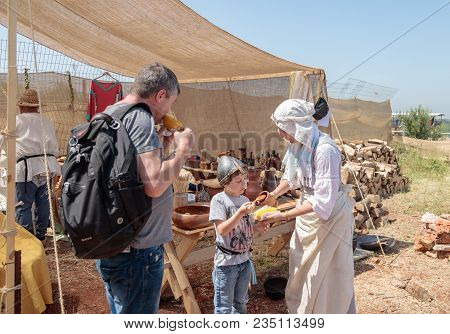 Goren, Israel, April 06, 2018 : A Participant In The Knight Festival Helps The Visitor Cook Boiled C