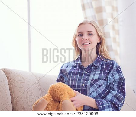We Are Happy To Regain Our Childhood. Happy Teenage Girl Playing With Teddy Bear Sitting On Sofa. We