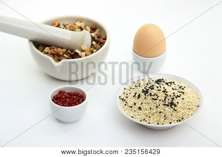 Keto Crackers Recipe Ingredients. Walnuts In Mortar For Grinding, Egg, Black And White Sesame Seeds,