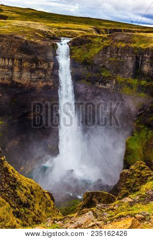 Cloudy and windy summer day in Iceland. Complex of high waterfalls of Haifoss in a dangerous tundra canyon. The concept of extreme and phototourism