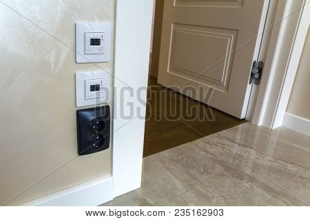 Modern House Interior With Warm Floor Controller Panels On The Wall, Wooden Parquet And White Door