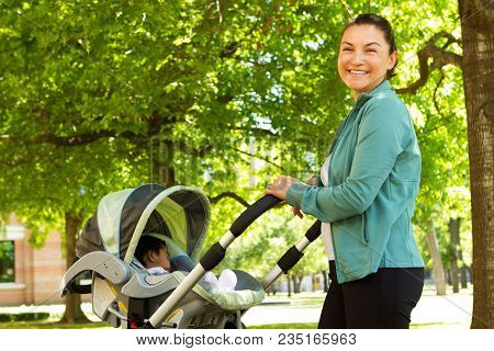 Hispanic Mom Pushing Her Baby In A Stroller.