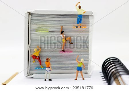 Miniature People Climbing Book With Challenging Route On Cliff, Concept Of The Path To Purpose And S
