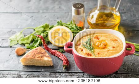 Freshly Made Hummus In A Purple Bowl And Six Cherry Tomatoes On A Dark Wooden Table. Vegetarian Midd