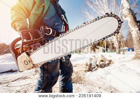 Chainsaw. Close-up Of Man Lumberjack Holding Chainsaw For Cutting Down Trees.