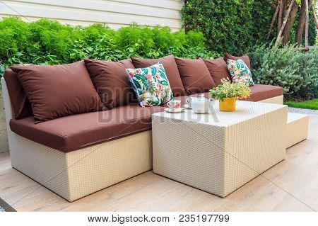 White Tea Set And Orange Flowers In Yellow Pot On Beige Resin Table And Beige Resin Sofa With Nature