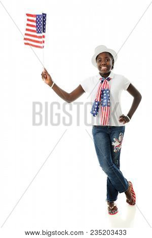 A happy American tween holding a flag while proundly wearing her stars and stripes. On a white background.