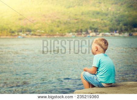 Cute caucasian boy at seaside. Rear view. Leisure time
