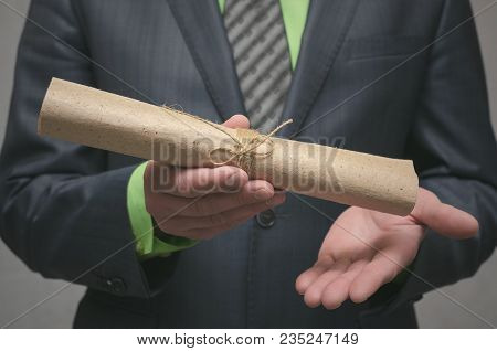 Businessman Holds In Hand A Rolled Up Document Scroll. Signing Of An Agreement. Conclusion Of A Busi