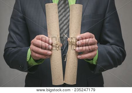 Businessman Holds In Hand A Rolled Up Document Scroll. Signing Of An Agreement. Conclusion Of A Busi