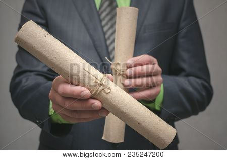 Businessman Holds In Hand A Rolled Up Document Scroll. Signing Of An Agreement. Conclusion Of A Busi