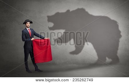Businessman standing with red cloth in his hand and big bear shadow on his background