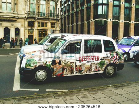 Great Britain, London, November 2012: The Taxi With Pin Up Motive Waiting At The Crossroads.