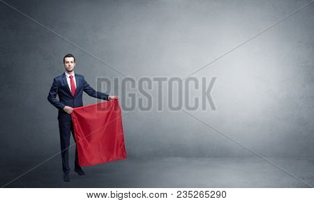 Businessman standing with red toreador cloth in his hand in an empty room