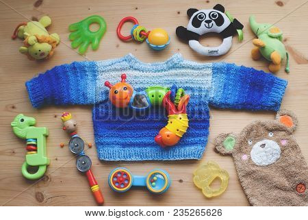 Niederstetten, Germany, February 2018: The Children Toys And Homemade Blue Sweater Lying On Wooden B