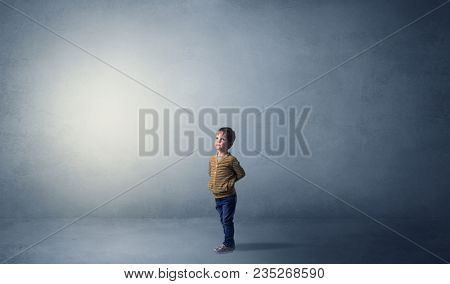 Little waggish kid staying alone in a big empty room with his plush