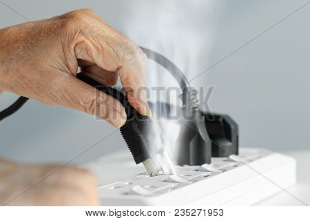 Elderly Hand With Electrical Outlet Spark At Home