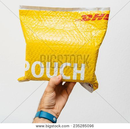 Paris, France - Mar 24, 2018: Male Hand Holding Against White Background A Dhl Express Yellow Parcel