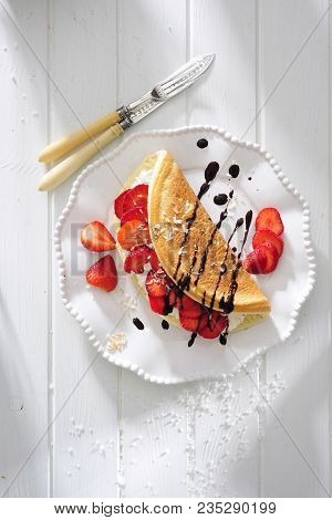 Omelette With Fresh Strawberry And Cream Filling Topped With Chocolade Sauce.