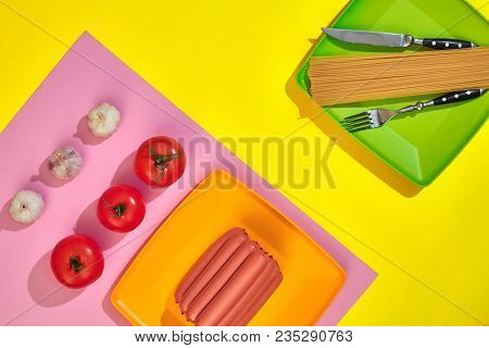 A Lot Of Raw Sausages On Plate. On Yellow Background With Pasta And Vegetables, Top View. Still Life