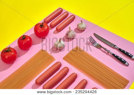 A Lot Of Raw Sausages With Pasta And Vegetables On Pink And Yellow Background, Top View. Still Life.
